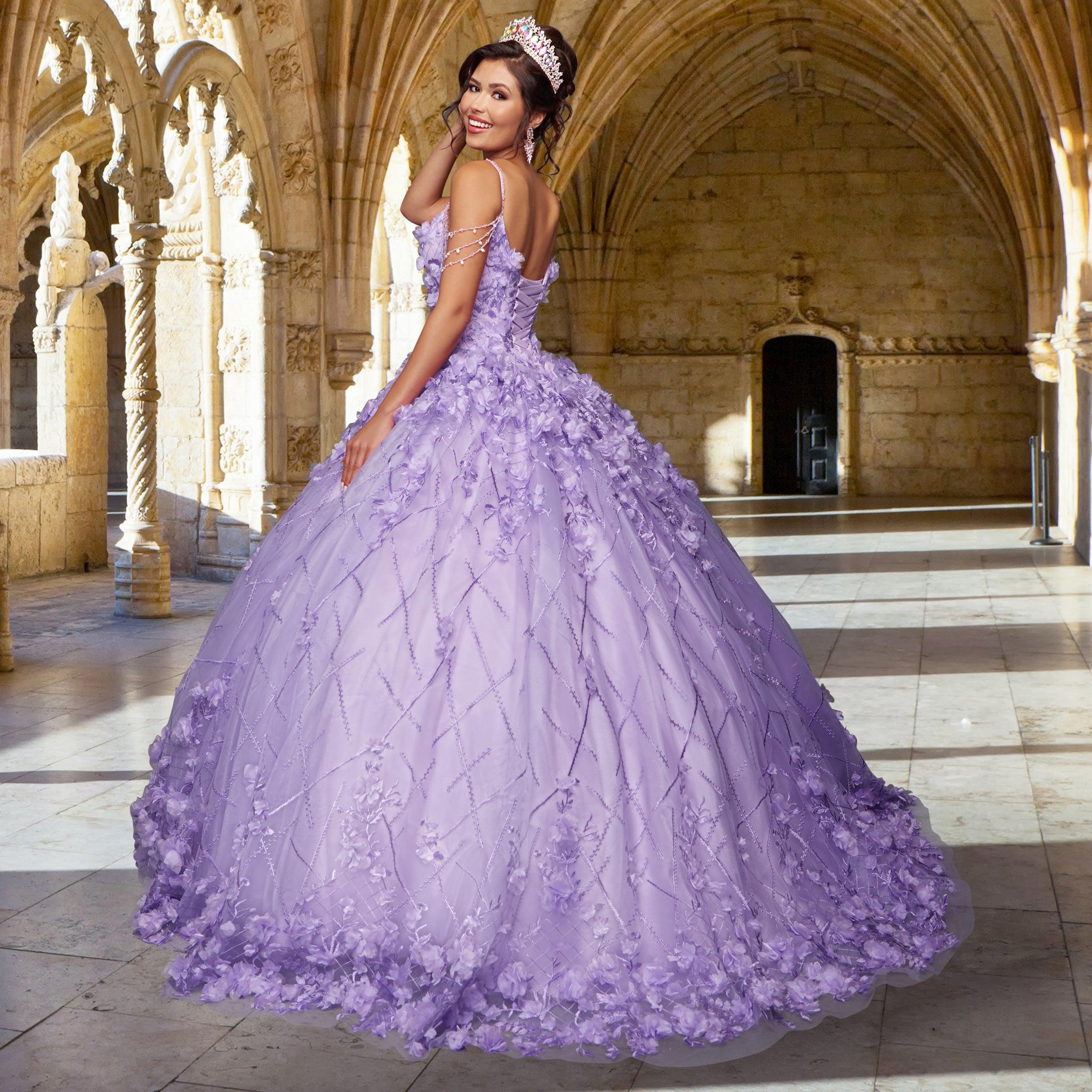 A young woman in the Quinceañera Sample Dress QF105 and a tiara stands in an ornate stone hall, looking back over her shoulder and smiling.